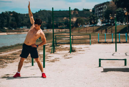 Young handsome sports man doing stretching before run at the beachの写真素材