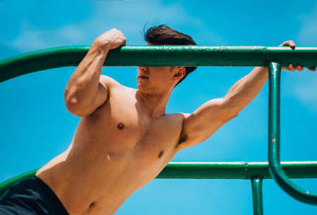 Young muscular bodybuilder working out in gym doing exercises parallel bars Concept sport