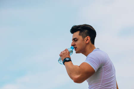Sporty man refreshing with cold water after run training in the park