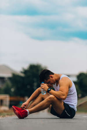 Young man relaxing after a running training session outdoors on sunny day