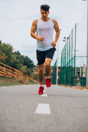 Headless rear view shot of an athletic young man running at the park