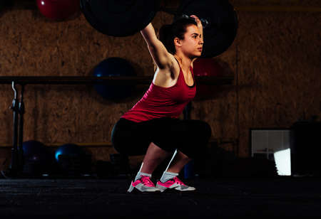 Good looking girl is raising barbell in the gym