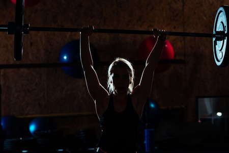 Young bodybuilder girl doing exercise in the gym