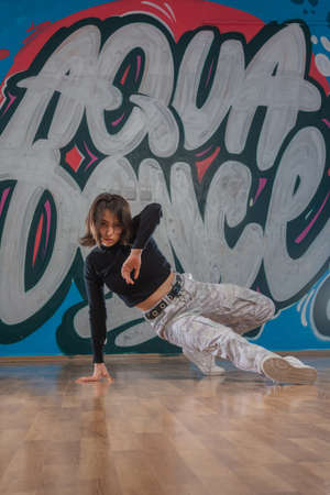 Attractive young woman doing breakdance move over graffiti background