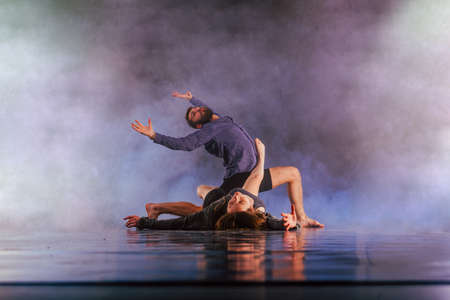 Shoeless dance couple performing multiple unique dance moves in front of a black background...