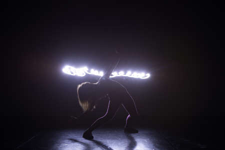 Modern art dancer, dancing in front of a black background with neon blue light while steching and twisting her body.の写真素材