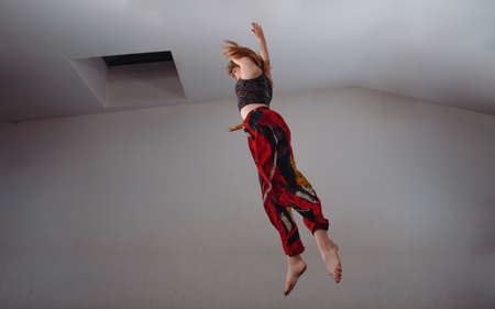 Caucasian female dancer exercising a contemporary dancing over white wall