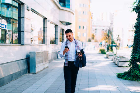 A man in suit is on the city square, looking around him and talking to his mobile phone.の写真素材