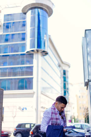 Businessman is standing in the city center near the cafe and looking interested in his notebook.の写真素材