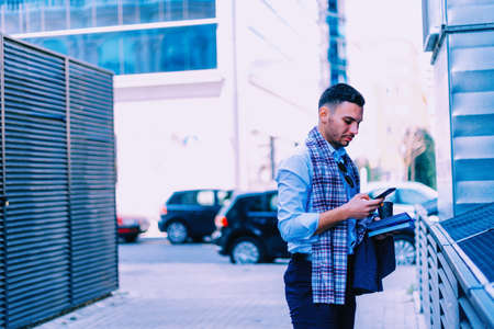 Businessman is standing in the city center near the cafe and looking interested in his notebook.の写真素材