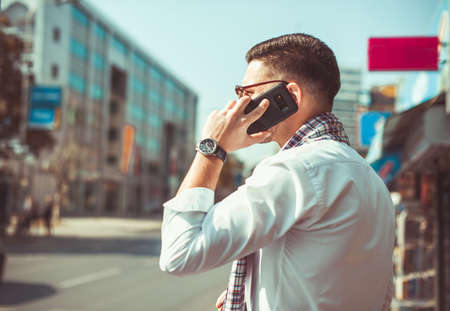 Caucasian businessman is standing in urban city next to the pedestrian crossing, he is having a phone callの写真素材