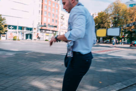Young modern businessman is outside, walking in the city while looking around.の写真素材