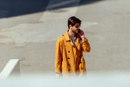 Businessman wearing yellow coat standing at city squareの写真素材