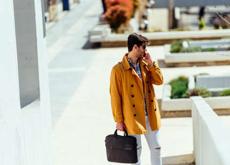 Young handsome manager in yellow coat going to work