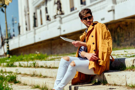Businessman wearing yellow coat working on pc tablet otudoorsの写真素材