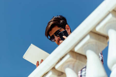 Portrait of a smiling businessman walking and talking on mobile phoneの写真素材