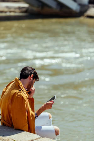 Urban businessman with stylish clothing sitting on stairs and talking on mobileの写真素材