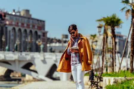 Modern handsome manager in yellow coat with pc tablet and cellphoneの写真素材