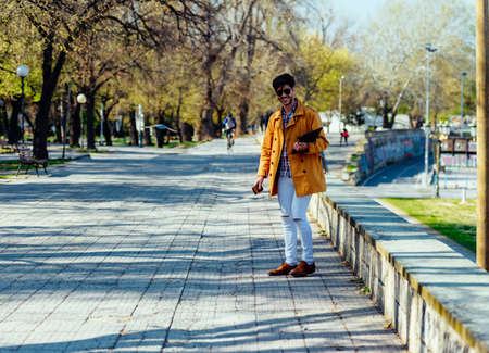 Happy businessman wearing yellow coat is standing in the parkの写真素材