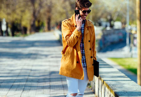 Young businessman is walking and talking on phoneの写真素材