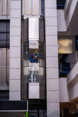 Handsome businessman is going up with the elevator while comunicating on his phone