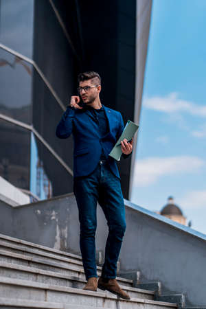 Businessman in blue suit with notebook waking down the square