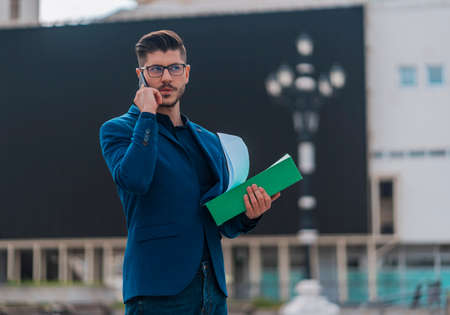 Portrait of a smiling businessman walking and talking on mobile phoneの写真素材