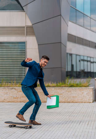 Businessman in blue businesssuit on longboard walking with folder in his hand. Freelance man...