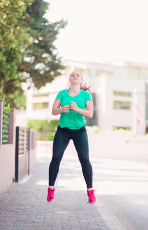 Full body portrait of an active young woman stretching outside
