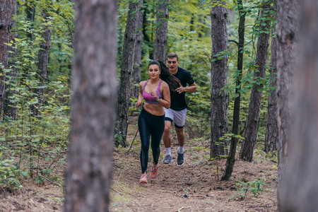 Fit male and female athletes running in nature. Nature and sports concept.