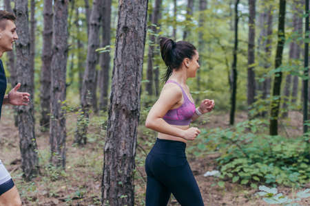 Fit male and female athletes running in nature. Nature and sports concept.