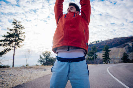 Fit masculine men stretching in the morning and preparing for exercise while looking at the urban city in the valley.の写真素材
