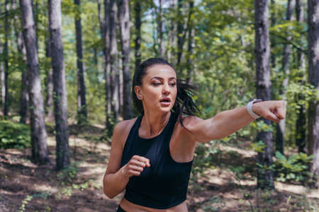 Close up portrait of a sexy brunette exercising kickbox with direct punches in the middle of the forestの写真素材