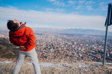 Strong male in his 20s stretching in the morning at winter while looking at his hometown in the valley.の写真素材