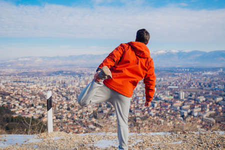 Strong male in his 20s stretching in the morning at winter while looking at his hometown in the valley.の写真素材