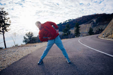 Fit masculine men stretching in the morning and preparing for exercise while looking at the urban city in the valley.の写真素材