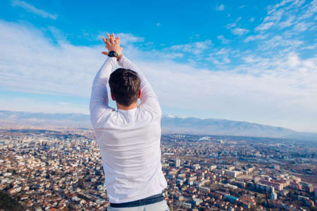 A young strong fit masculine man working out in the morning while looking at the city.の写真素材