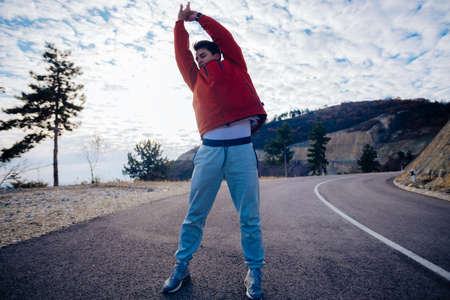 Fit masculine men stretching in the morning and preparing for exercise while looking at the urban city in the valley.の写真素材