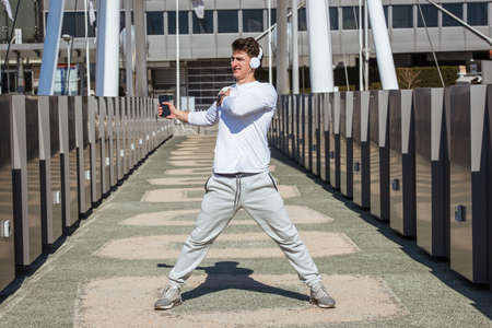 Attractive man warming up and prepare for jogging on the bridge