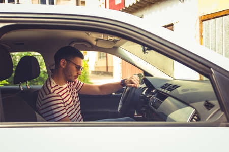 Man in his car in some neighborhood looking downの写真素材