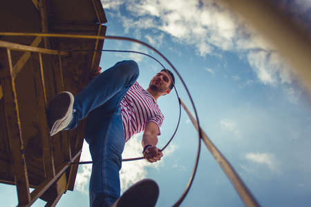 Man climbing on metal stairs near by metal tubes, looking calm and peacefulの写真素材