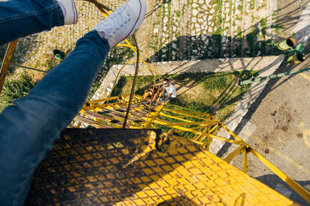 A man is balansing and sitting on a high construction, enjoying the view od the city panoramaの写真素材