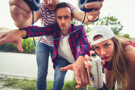 Three friends are fooling around and having fun with spray at urban placeの写真素材