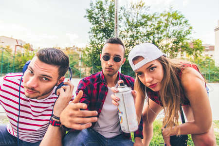 Three urban people looking serious with spray color are spending time together