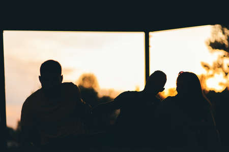 Friends are having fun fooling around and hugging their legs in the park, enjoying the sunset viewの写真素材