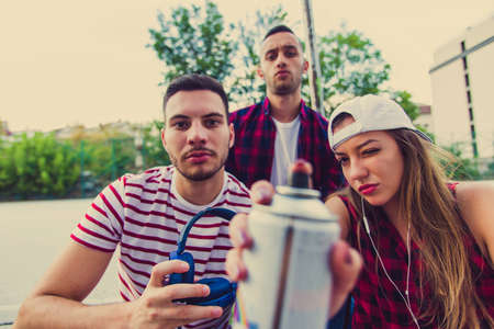 Three urban friends with spray color are having time together, looking seriousの写真素材