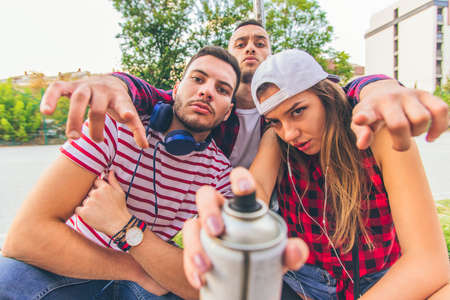 Three friends are fooling around and having fun with spray at urban placeの写真素材