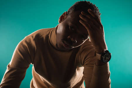 Close up portrait of handsome and young black male posing on blue backgroundの写真素材