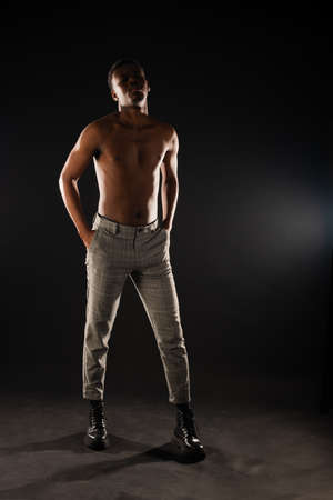African black male is standing while posing on black backgroundの写真素材
