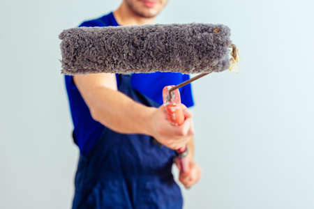 Portrait of handsome painter while holding paint roller on white backgroundの写真素材